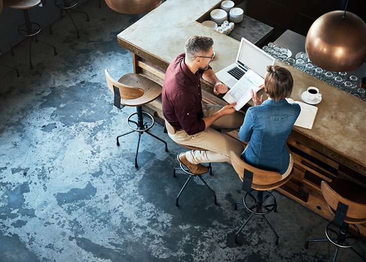 High angle shot of two businesspeople working at the bar in a cafe